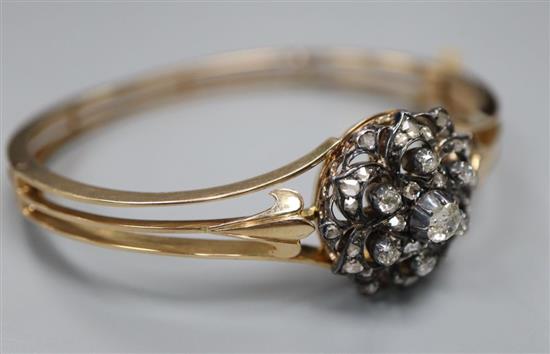 An early 20th century pierced yellow metal and diamond cluster set hinged bracelet, with safety chain, gross 21.7 grams.